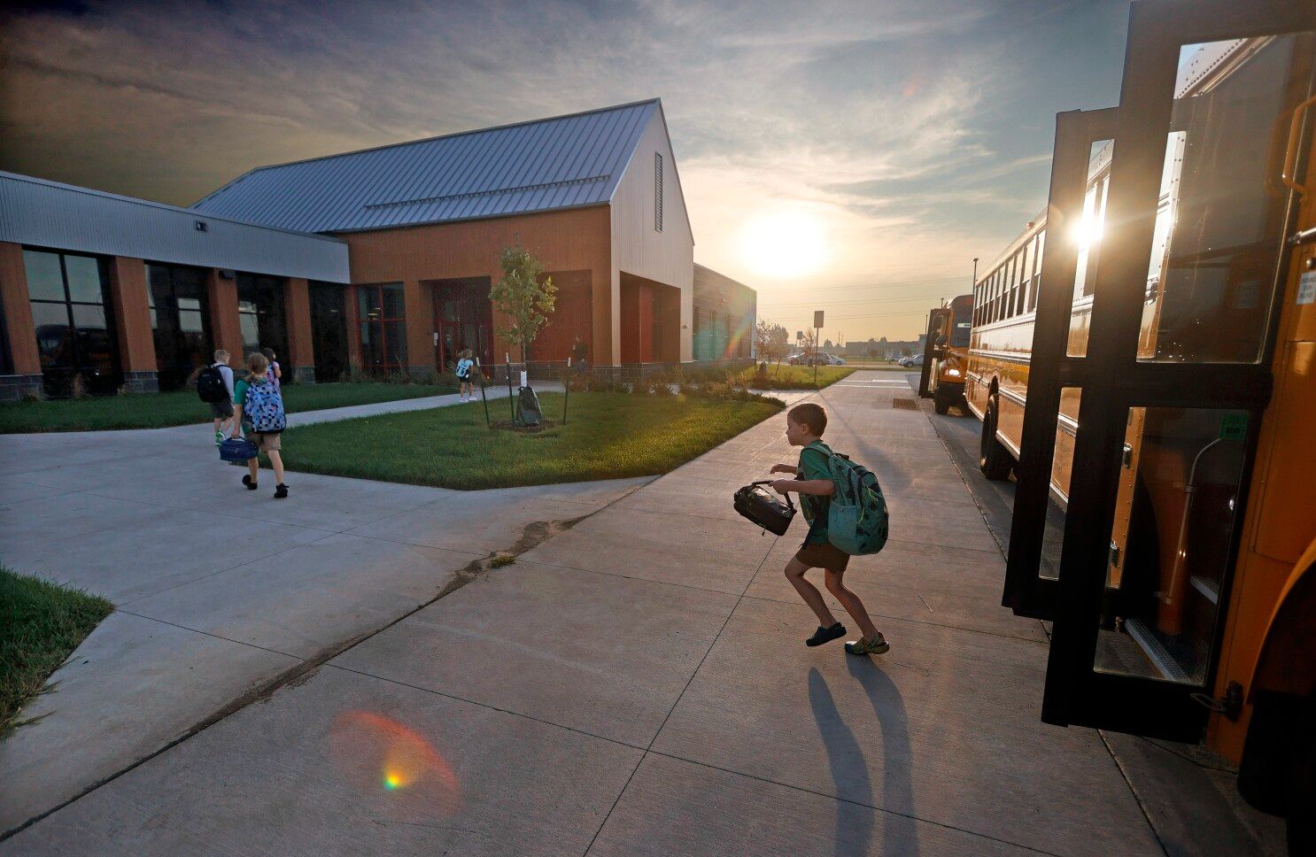 Child getting off of bus with sunset