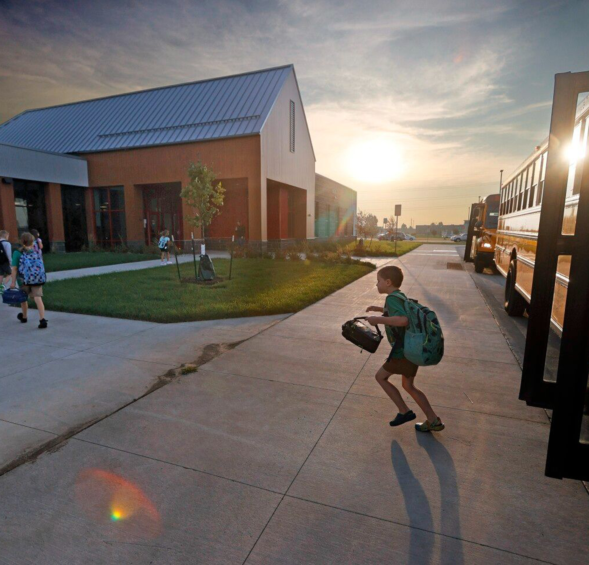 Child getting off of bus with sunset